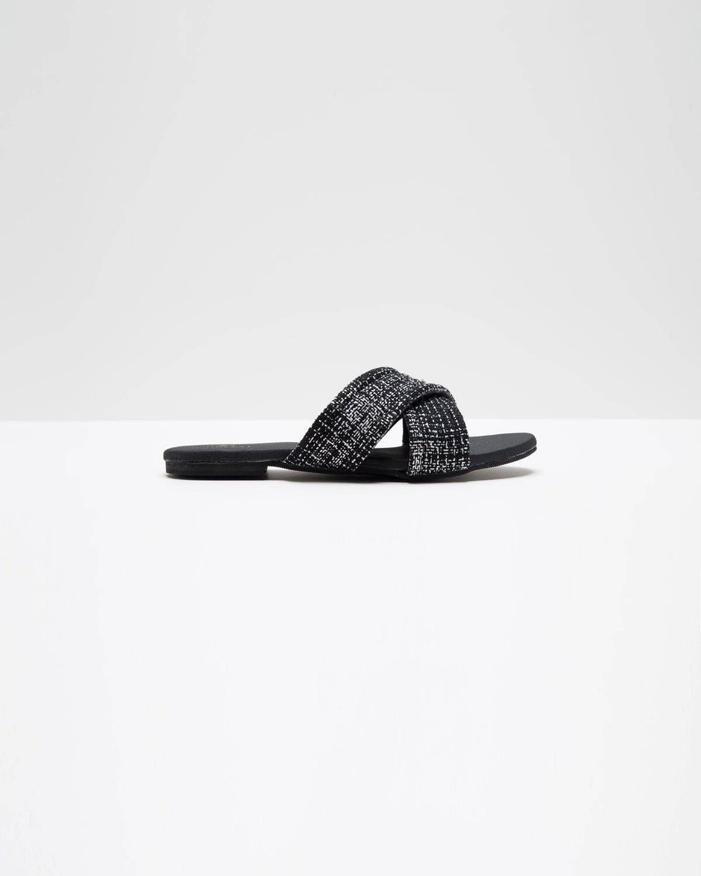 Windlust black jute cross-strapped flats with open toe and flat sole, showcasing stylish, comfortable footwear design.