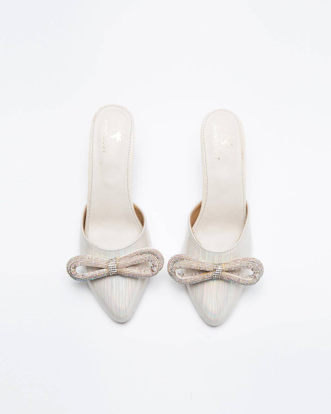 Metallic cream embellished bow heels by Windlust, featuring a stylish design with decorative accents and a pointed heel.