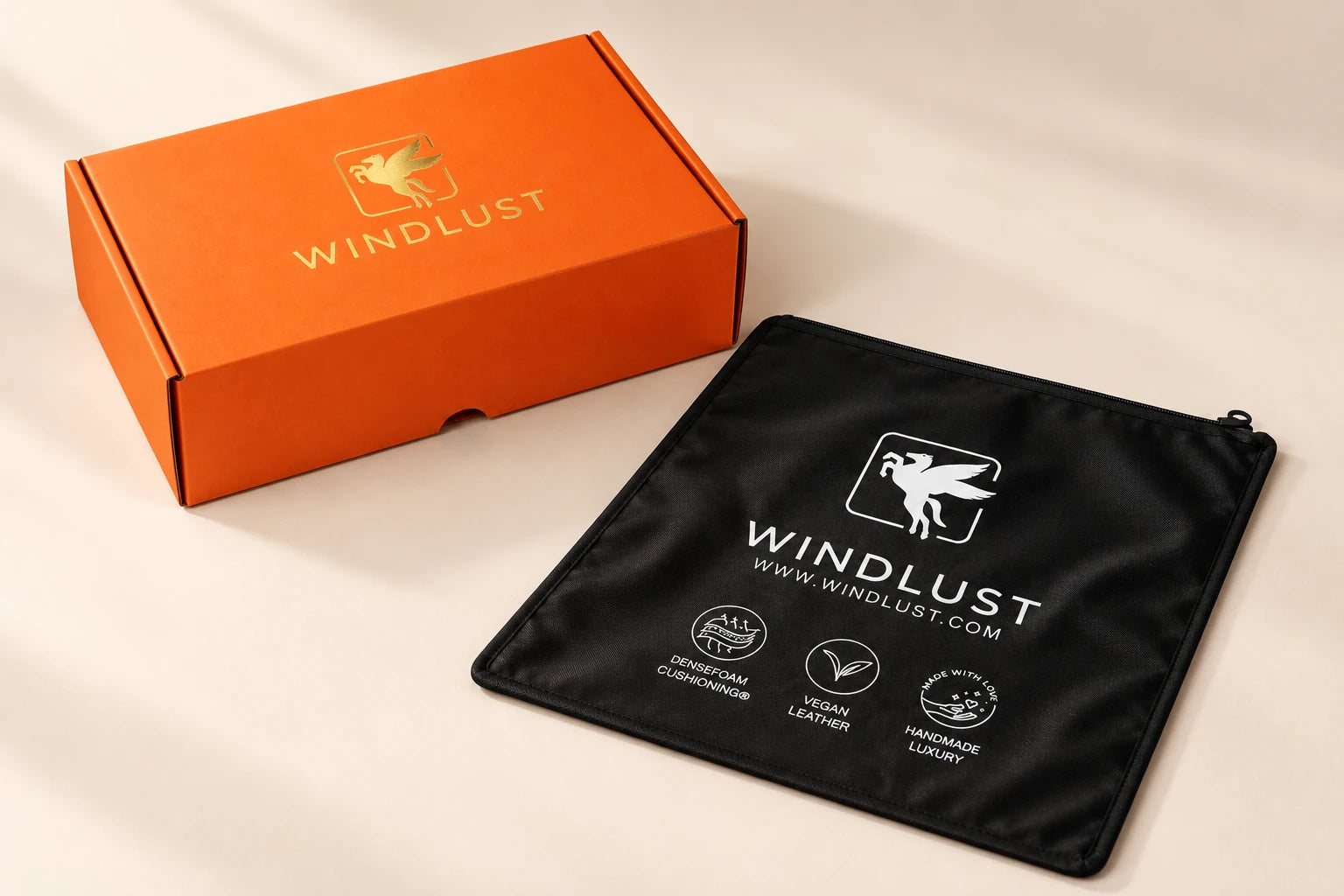 Windlust’s signature orange fold-top shoe box with its gold foil house emblem, beside the black zippered Windlust shoe bag.